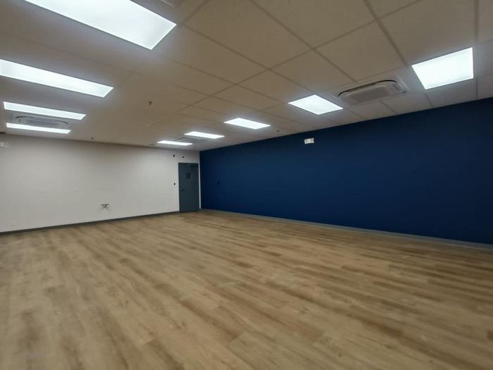 Oficina recién limpiada, piso laminado y pared azul, lista para ocupar