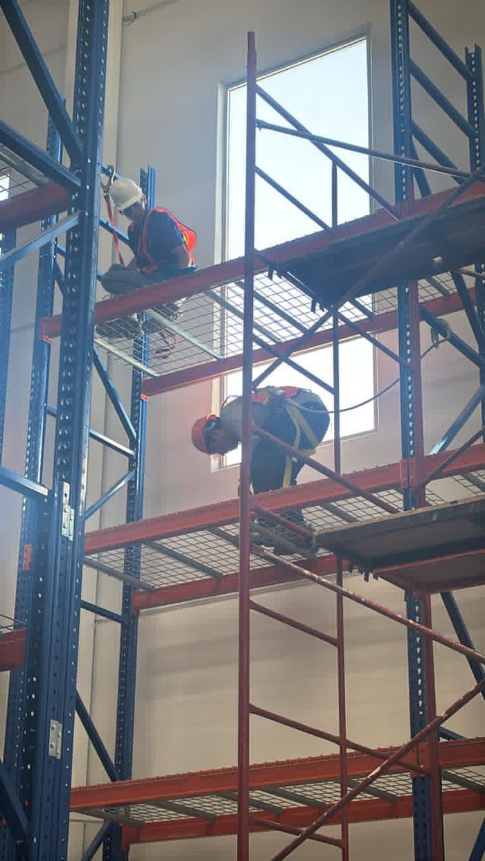 Personal de Satera en trabajo en altura sobre racks industriales, con equipo de seguridad