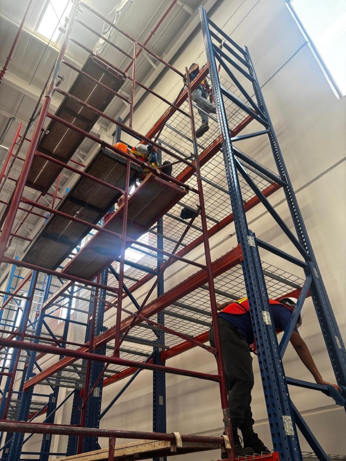 Personal de Satera en trabajo en altura sobre estructura de racks, vista desde abajo