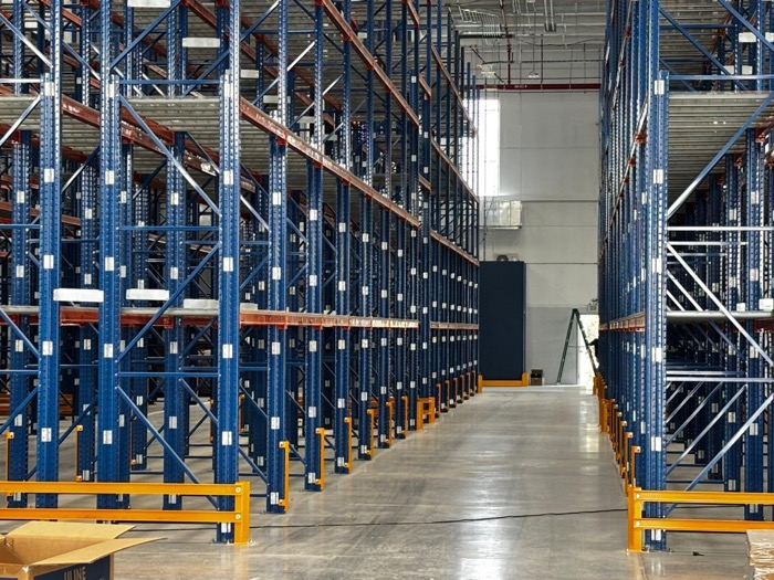 Pasillo de racks industriales con barandales de seguridad naranjas, instalación limpia y ordenada
