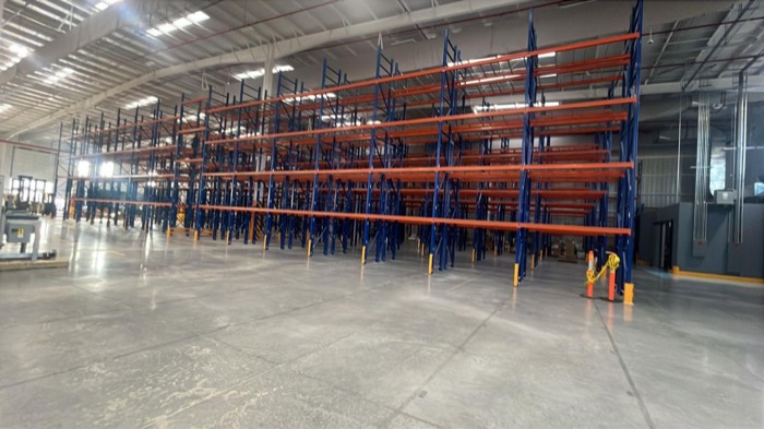 Estructura de racks industriales vacía y ordenada en nave con piso de concreto pulido